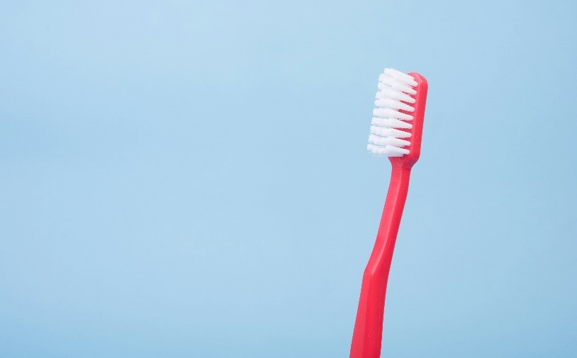 A red toothbrush with white bristles

Description automatically generated